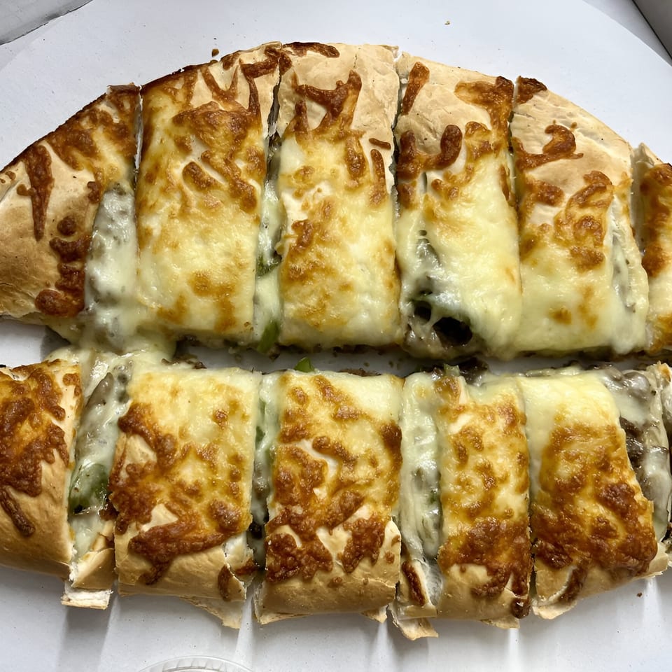 Two rows of sliced calzones, filled with cheese and meat, in a white box from Hudson House of Pizza.
